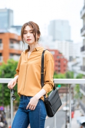 Ms. Hinaka Tsurukubo is wearing orange long-sleeved blouse and jeans, black bag, she is standing on the footbridge, she is a Japanese & Asian mature beauty fashion model, her height is 171 cm, her figure is very pretty.