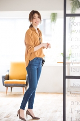 Ms. Hinaka Tsurukubo is wearing orange long-sleeved blouse and jeans, she is standing in the room, she is a Japanese & Asian mature beauty fashion model, her height is 171 cm, her figure is very pretty.