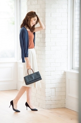 Ms. Hinaka Tsurukubo is wearing a blue cardigan, brown short-sleeved blouse, white skirt, black shoes, carrying a small black bag, she is standing in the room, she is a Japanese & Asian mature beauty fashion model, her height is 171 cm, her figure is very pretty.