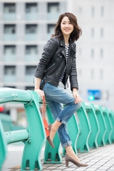 Ms. Keina is wearing a black jacket, jeans, she is sitting on the green guardrail, she is a Japanese & Asian mature beauty fashion model, her height is 170 cm, she is very slim and beautiful, elegant.