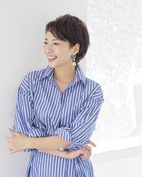 Ms. Tamaki is a mature Japanese & Asian female fashion model wearing a blue and white striped dress, and she is standing with her eyes turned to the side.
