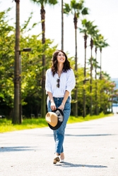 Ms. Hikane Doki is wearing a light blue tailored shirt, she is wearing jeans, sunglasses on her chest, and a straw hat in her hand, she is a Japanese & Asian beautiful fashion model.