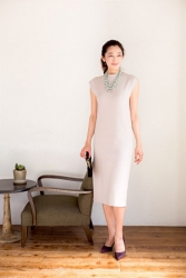 Ms. Namiri Ishiba is wearing a white dress with a light green necklace hanging around her neck, she is standing by the chair and table, she is a Japanese & Asian beautiful and elegant mature female fashion model.