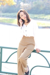 Ms. Namiri Ishiba is wearing a white long-sleeved blouse and ochre trousers, she is sitting on the green guardrail, she is a Japanese & Asian beautiful and elegant mature female fashion model.