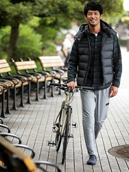 Mr. Hiroaki Kyusogami is wearing dark green jacket and gray pants and there is a bicycle next to him, he is walking, he is a handsome Japanese (Asian) actor and fashion model.