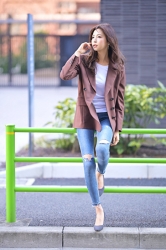 Ms. Akie is a Japanese & Asian fashion beauty model wearing a reddish brown blazer, white shirt, blue jeans, she sits on a yellow-green guardrail.