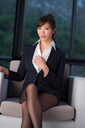 Ms. Eira Matsukage wears navy blue women's suit and white blouse, black stockings, she is sitting on the sofa, her bust is 87 cm, she is slim and graceful, she is a Japanese & Asian sexy and beautiful breast swimsuit female model, she is a sexually attractive woman.