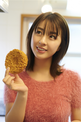 Ms. Yurine Yanagioka is wearing a red sweater and has instant noodles in her hand, she is a Japanese & Asian actress, gravure idol (bikini model, swimsuit model, swimwear model, pin-up girl), TV personality, her bust is 84 cm, and she has beautiful breasts.