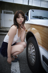 Ms. Yurine Yanagioka is wearing a white shirt, blue skirt, next to the car, she is crouching, she is a Japanese & Asian actress, swimsuit model (bikini model, swimsear model, gravure idol), TV personality, her bust is 84 cm, she has beautiful breasts.