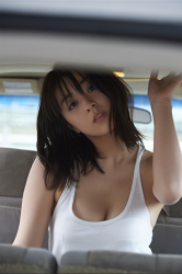 Ms. Yurine Yanagioka is wearing a white shirt, blue skirt, and in the car, she is a Japanese & Asian actress, bikini model (gravure idol, swimwear model), TV personality, her bust is 84 cm, and she has beautiful breasts.