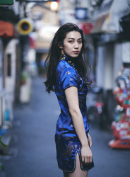 Ms. Aisui Saito is wearing a blue cheongsam, she is standing on the road, she is a beautiful and sexy Japanese & Asian gravure idol (bikini model, swimsuit model, pin-up girl), actress, her bust is 85 cm, she has beautiful breasts, she is a woman with sexual charm.