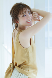Ms. Naasu Takamichi is a young Japanese & Asian fashion model and actress wearing a tawny shirt and beige pants, she is standing by the window.
