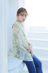 Ms. Naasu Takamichi is a young Japanese & Asian fashion model and actress wearing a yellow-green blouse and jeans, she is sitting.