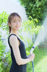 Ms. Naasu Takamichi is a young Japanese & Asian fashion model and actress wearing a dark blue dress, and she is watering with a hose.