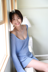 Ms. Neiro Shii is a very cute Japanese & Asian beautiful and cute young bikini model (gravure idol, swimsuit model, pin-up girl), TV personality, freelance announcer, wearing a light blue long-sleeved shirt, she is sitting.