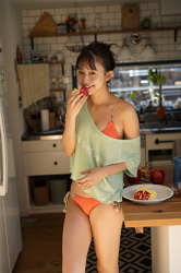 Ms. Neiro Shii is a very cute young Japanese & Asian bikini model (gravure idol, swimsuit model, pin-up girl), TV personality, freelance announcer, wearing a yellow green shirt, orange bikini, she is in the kitchen, standing and eating an apple.