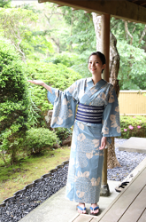 Ms. Amiho Tsumuji wears a light blue yukata, she is standing under Japanese style architecture, she is a beautiful and sexy bikini swimsuit model from Japan, her bust is 88cm, she has big breasts, beautiful breasts.