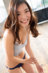 Ms. Amina Hachitsuka is a Japanese & Asian beautiful fashion model, TV personality, actress, gravure idol (bikini model, swimwear model, pin-up girl) wearing gray camisole, blue pants, she is standing in the room.