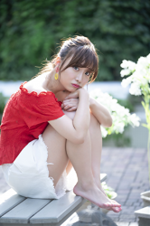 Ms. Ayaka is wearing a red short-sleeved blouse and white shorts, she is sitting on the floor grasping her knees, she is a beautiful & cute Japanese & Asian model, freelance announcer, TV personality.