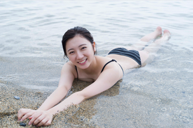 Ms. Kirara wears a black bikini swimsuit, she lies face down on the beach, she used to be an idol singer, she is a sweet and cute Japanese & Asian gravure idol (bikini model, swimsuit model pin-up girl) and actress.