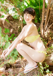 A Japanese & Asian gravure idol (pin-up girl), actress, and singer wearing a yellow bikini, her name is Ms. Mikoto, she is crouching on a log.