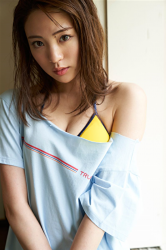 Standing in a light blue shirt and a yellow bikini, Ms. Yuina is a Japanese & Asian fashion model, actress and swimsuit model (gravure idol, bikini model).