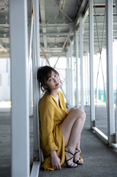 Ms. Misui Shiokaramatsu wears a yellow robe, she is outdoors, she is sitting in the building, she is a mature and elegant bikini swimsuit beauty, she is a beautiful and sexy Japanese & Asian freelance announcer, mature swimsuit model, her bust is 88cm, she has big breasts, she is a sexually attractive woman.