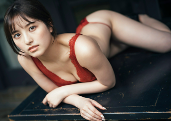 Ms. Nanane Oka is wearing a red lingerie, she is lying face down on a black table, she is a beautiful and cute Japanese & Asian gravure idol (bikini model, swimsuit model, pin-up girl) and actress.
