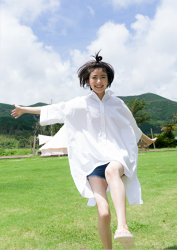 Ms. Natsuyo Ikekatsu wears a big white tailored shirt & denim shorts, she is walking on the grassy playground, she is a beautiful and cute model & actress in Japan.