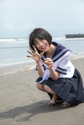 Ms. Natsuyo Ikekatsu is wearing a school uniform, and she is squatting on the sandy beach, she is a Japanese & Asian beautiful and cute model & actress.
