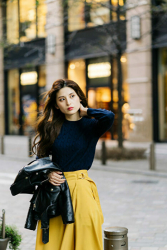 Ms. Atsumi Aonami is wearing a dark blue long-sleeved blouse, yellow skirt with a leather jacket in her hand, she is standing in the street, she is a beautiful, elegant and mature Japanese & Asian fashion model, her height is 173 cm, and her figure is very slim and pretty.