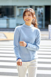 Ms. Akie Shibukawa is a beautiful Japanese & Asian fashion model, wearing a light blue blouse and white pants, she is crossing a pedestrian crossing in a certain town.
