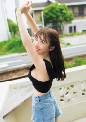Ms. Emina is a Japanese and Asian gravure idol (swimwear model, bikini model, pin-up girl), TV personality and singer, she is wearing a black tank top and denim shorts and she is standing with her arms raised.