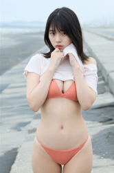 Ms. Kiira Kikuoki a Japanese & Asian gravure idol (swimwear model, bikini model, pin-up model) and actress, she is at the beach and is wearing an orange bikini and white t-shirt.