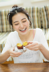 Ms. Mariho Kokei is a Japanese & Asian fashion model, swimsuit model (gravure idol / bikini model / pin-up girl), actress, and former idol, she is wearing a white shirt and she is sitting and holding a baked potato.