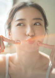 Ms. Mariho is a Japanese & Asian fashion model, swimsuit model (gravure idol), actress, and former idol, this is a photo of her face only, she puts her index finger to her cheek.