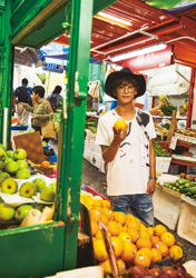 Mr. Ayato Akaibashi is wearing a white shirt and jeans and is at a fruit market in Hong Kong, he is also an actor and voice actor.