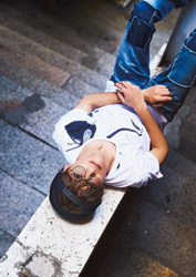 Mr. Ayato Akaibashi is wearing a white shirt and jeans and is lying on a street corner in Hong Kong, he is also an actor and voice actor.