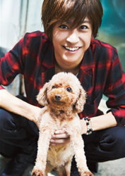 Mr. Ayato Akaibashi is wearing a red checkered cutter shirt and holding a dog in his hand, he is also an actor and voice actor.