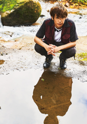 Mr. Ayato Akaibashi is wearing a dark cut shirt and pants and is squatting by a puddle, he is also an actor and voice actor.