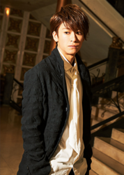 Mr. Ayato Akaibashi is standing in a black suit with a white shirt and white tie, he is also an actor and voice actor.