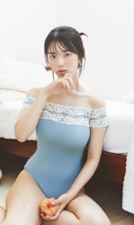 Ms. Kiira Kikuoki is a Japanese & Asian gravure idol (swimwear model, bikini model, pin-up model) and actress, she is wearing a blue leotard, holding a peach, and sitting under the bed.