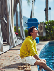 Mr. Takaatsu Sakurahaba is sitting by the pool wearing yellow clothes and beige shorts, he is a handsome Japanese & Asian actor, fashion male model.