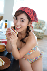 Ms. Yaaya Igeta is wearing a colorful bikini with a red cloth around her head, sitting by the kitchen, she is about to eat a sandwich, she is a Japanese & Asian gravure idol (bikini model, swimsuit model, pin-up girl), actress, TV personality, her bust is 92 cm, she has attractive big breasts, she is a sexually attractive woman.