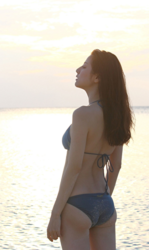 Ms. Yumika Sugiomi is wearing a blue bikini and standing by the sea, showing her back view, she is a beautiful and elegant Japanese & Asian fashion model, gravure idol (bikini model, swimsuit model, pin-up girl), actress, female singer, her bust is 84 cm, she has beautiful breasts, she has attractive women.