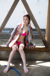 Ms. Haruko Tsubamoto is a Japanese & Asian busty gyaru swimsuit model (gravure idol / bikini model), dancer, and TV personality, she is wearing a pink bikini swimsuit with a brown bath towel over her body and she is sitting.