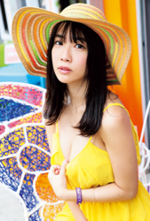 Ms. Kisara Amakura is a Japanese active idol, a very cute bikini model (gravure idol), an actress, and a TV personality, she is wearing a straw hat and a yellow dress and she is standing in the street.