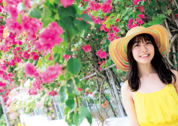 Ms. Kisara Amakura is a Japanese active idol, a very cute bikini model (gravure idol), an actress, and a TV personality, she is wearing a straw hat and a yellow dress and she is standing.