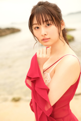 Ms. Makiko Tatsuhashi is wearing a red dress and standing on the sandy beach, she is an active idol singer and gravure idol (bikini model, swimwear model).
