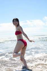 Ms. Uuna Tadekawa is a beautiful and cute young Japanese gravure idol (pin-up girl, swimwear model, bikini model), she is wearing a red bikini and is standing on the beach with her feet in the sea water.